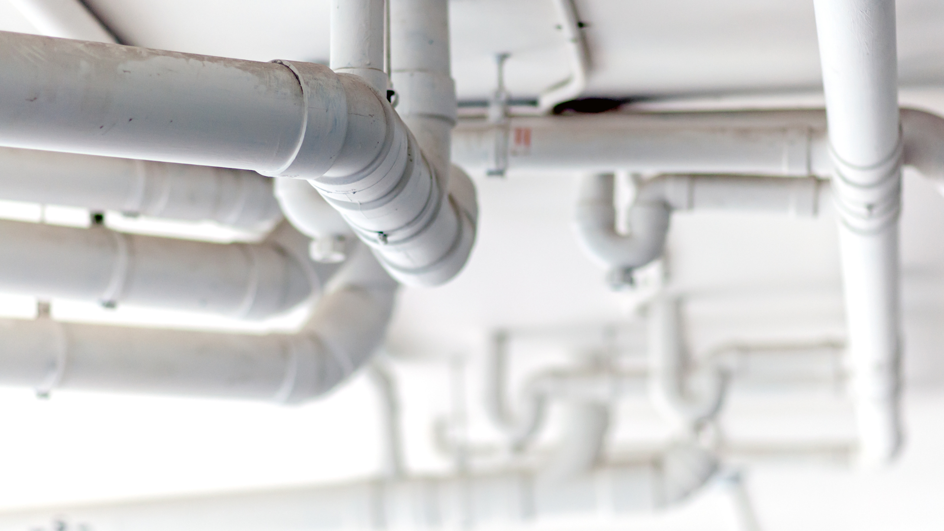 Plumbing and drainage pipework installed neatly along a ceiling run