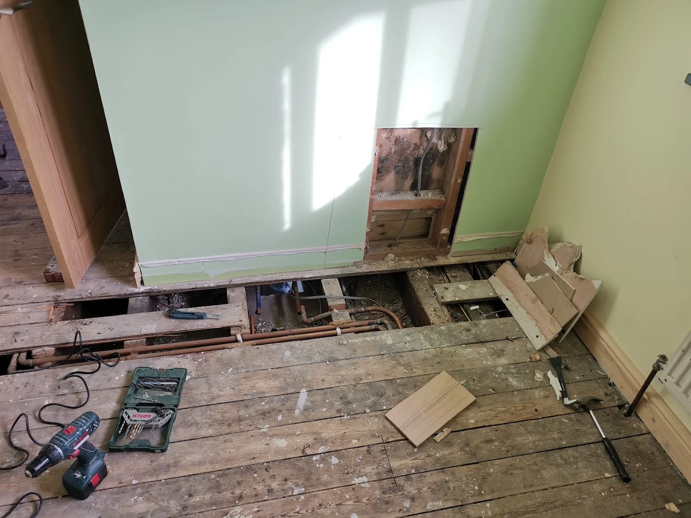 Floorboards lifted to trace a leak on concealed pipework during an emergency call-out