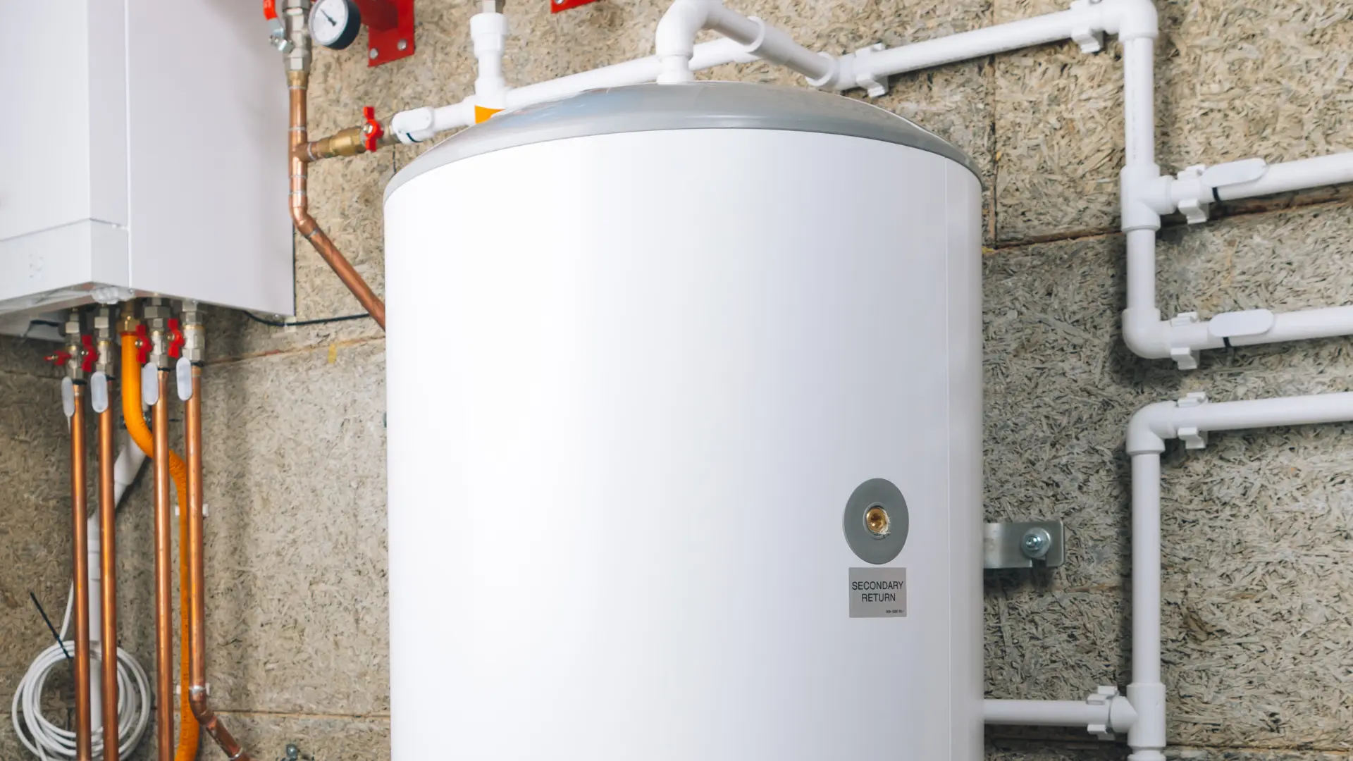 Unvented hot water cylinder installed with insulated pipework in a utility room