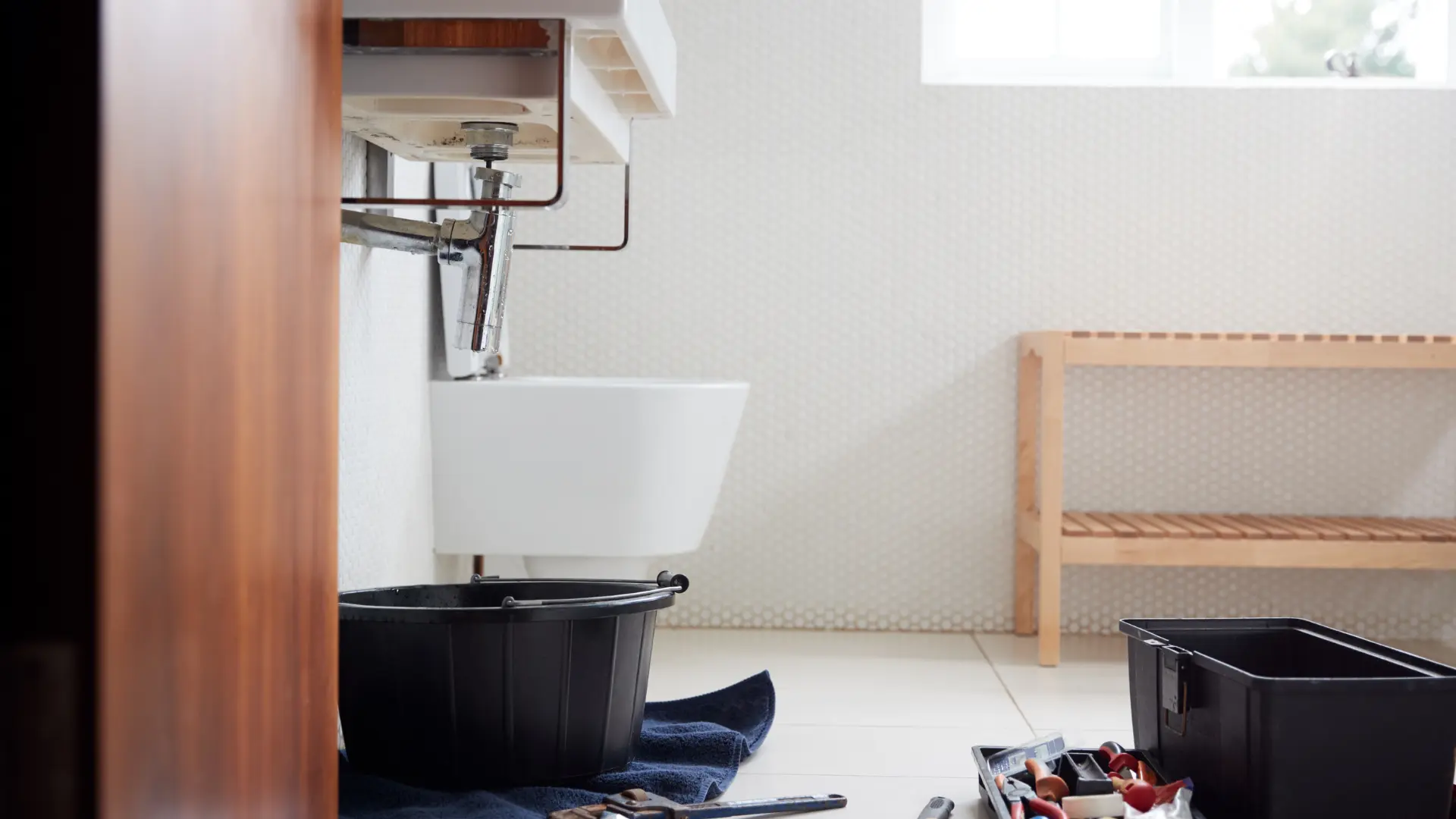 Emergency plumbing call-out to a leaking sink trap contained with a bucket