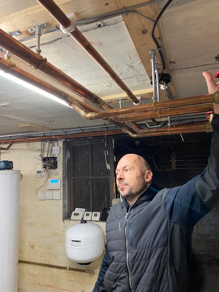 Engineer checking copper pipework, cylinder and controls during a gas safety inspection